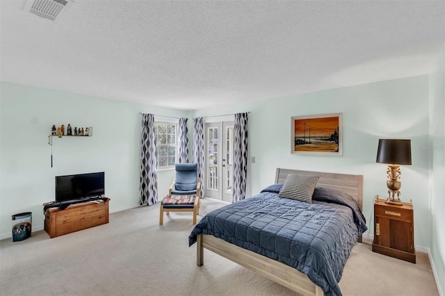 bedroom with baseboards, light colored carpet, visible vents, and a textured ceiling