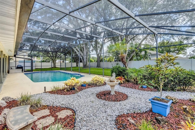 view of swimming pool with glass enclosure, a fenced backyard, and a fenced in pool