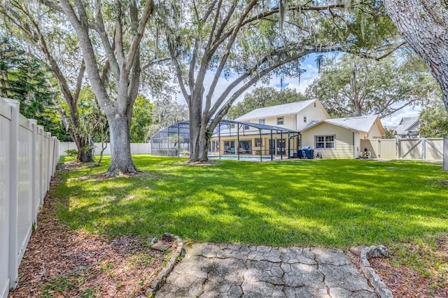 view of yard featuring glass enclosure, a gate, a fenced backyard, and a fenced in pool