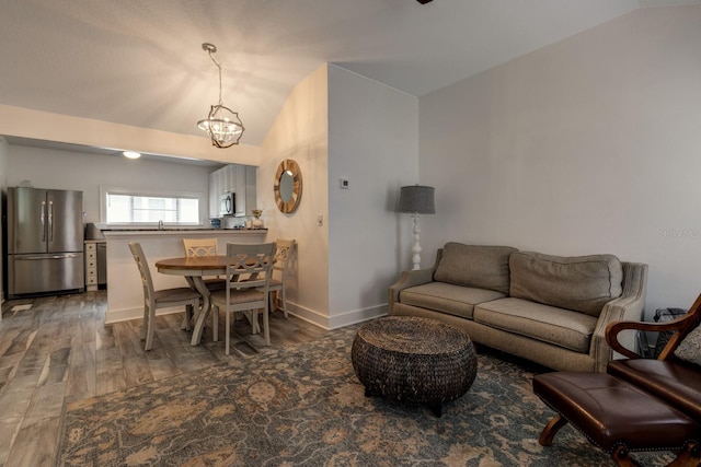 living room featuring sink, wood-type flooring, vaulted ceiling, and an inviting chandelier