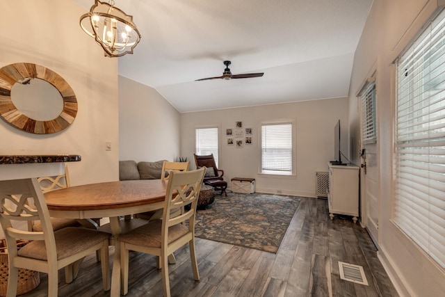 dining room featuring ceiling fan with notable chandelier, dark hardwood / wood-style flooring, and vaulted ceiling