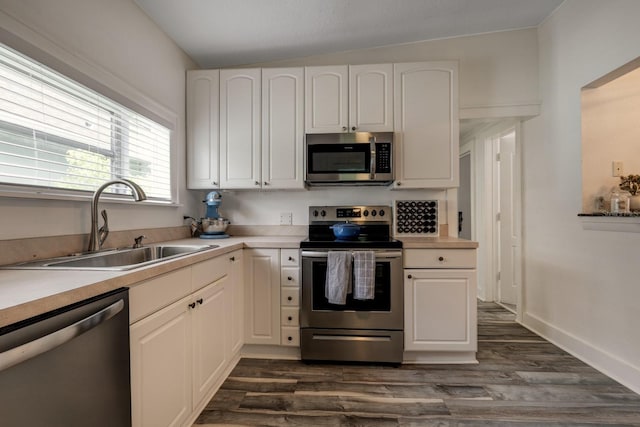 kitchen with stainless steel appliances, sink, dark hardwood / wood-style floors, white cabinetry, and lofted ceiling