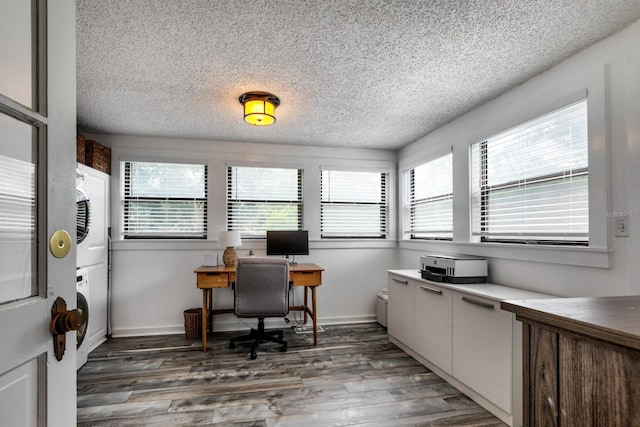 office space featuring dark wood-type flooring, plenty of natural light, and stacked washing maching and dryer