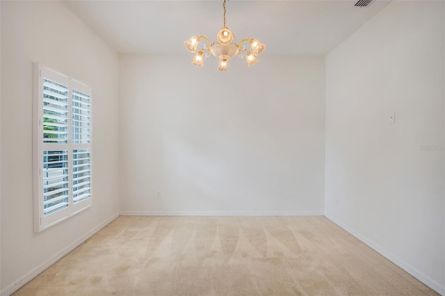 carpeted spare room with an inviting chandelier