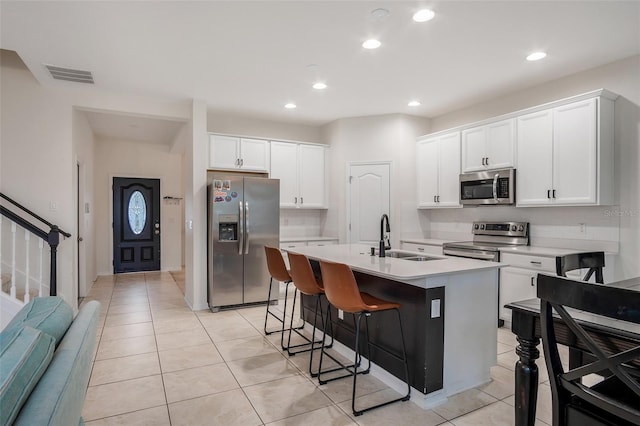 kitchen with sink, stainless steel appliances, an island with sink, a breakfast bar, and white cabinets