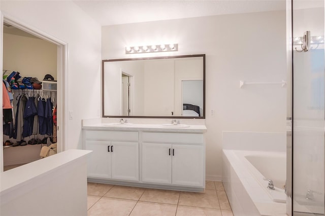 bathroom featuring tile patterned flooring, vanity, and tiled bath