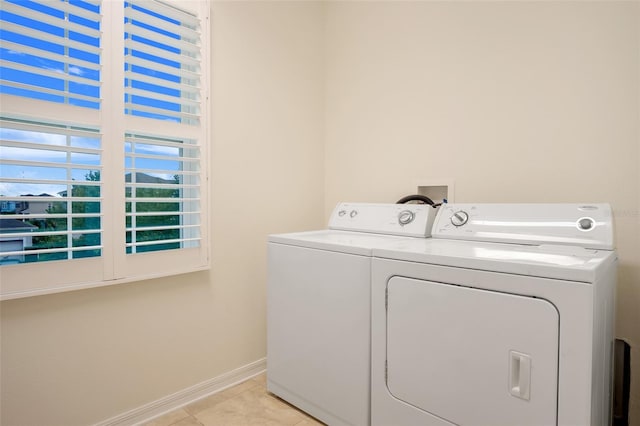 laundry area with washer and clothes dryer and light tile patterned floors