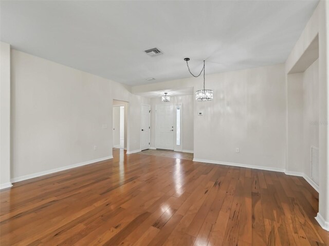 spare room featuring hardwood / wood-style floors and an inviting chandelier