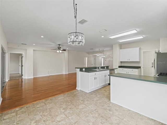 kitchen featuring white cabinets, stainless steel fridge, decorative light fixtures, and sink