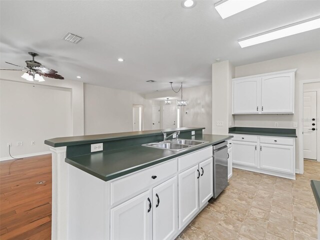 kitchen featuring ceiling fan with notable chandelier, sink, dishwasher, white cabinetry, and an island with sink