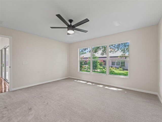 carpeted spare room featuring ceiling fan