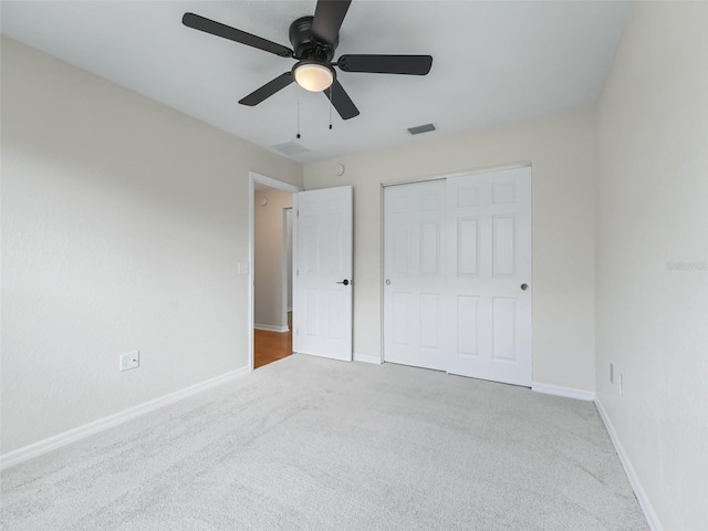 unfurnished bedroom featuring ceiling fan, light carpet, and a closet