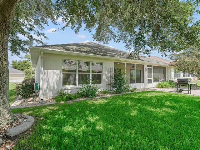 back of property with a yard, ceiling fan, and a sunroom