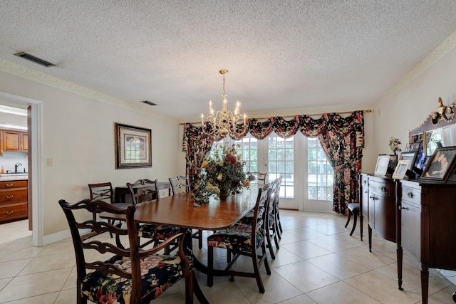 tiled dining room with sink, a chandelier, a textured ceiling, and crown molding