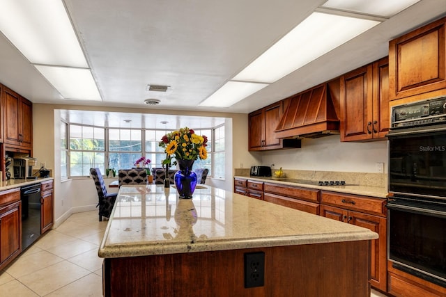 kitchen with black appliances, light stone counters, premium range hood, a kitchen island, and light tile patterned flooring