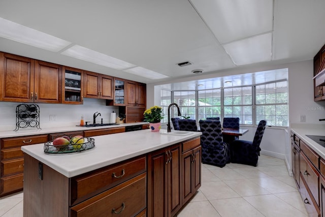 kitchen featuring sink, light tile patterned floors, and a center island with sink