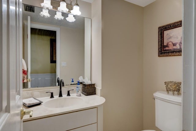 bathroom with vanity, a notable chandelier, and toilet