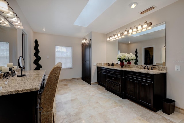 bathroom with a skylight, tile patterned floors, and dual bowl vanity