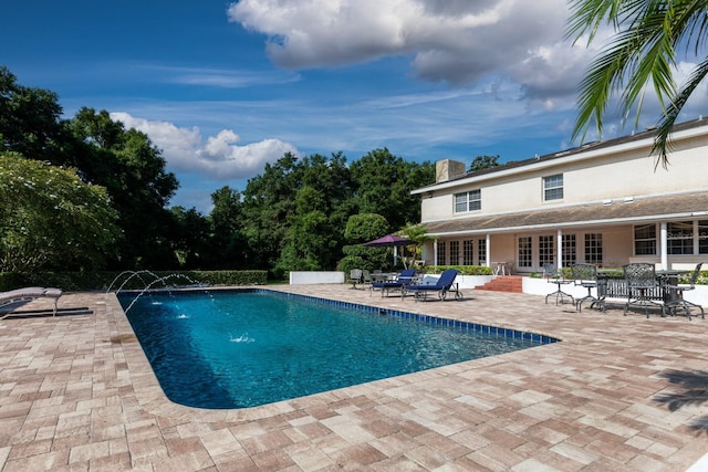 view of swimming pool with pool water feature, a patio, and french doors