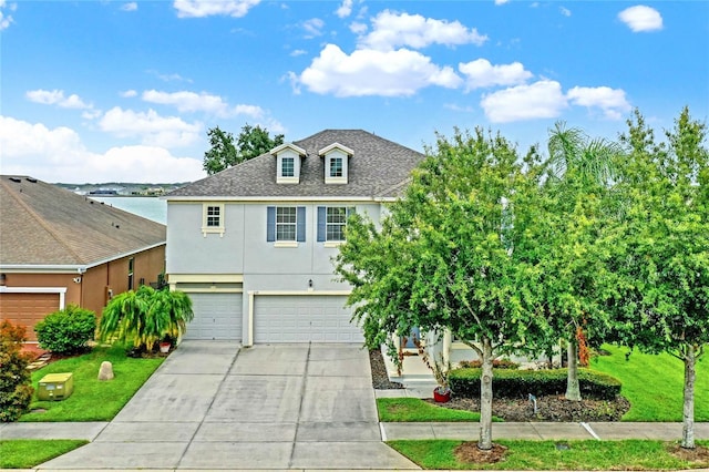 view of front of home featuring a front yard, a water view, and a garage