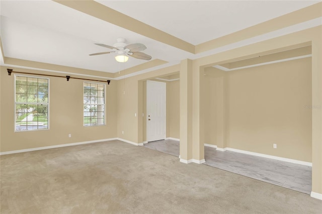 empty room featuring light colored carpet, ceiling fan, and a tray ceiling