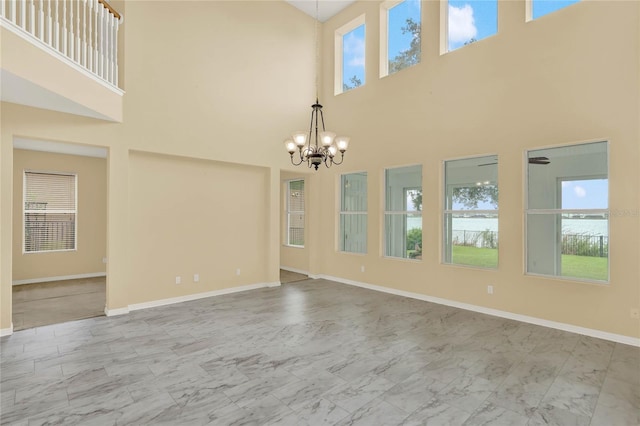 unfurnished room featuring a towering ceiling and a chandelier