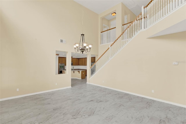 unfurnished living room featuring a notable chandelier and a high ceiling