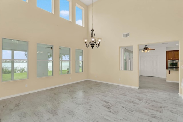 spare room featuring ceiling fan with notable chandelier and a high ceiling