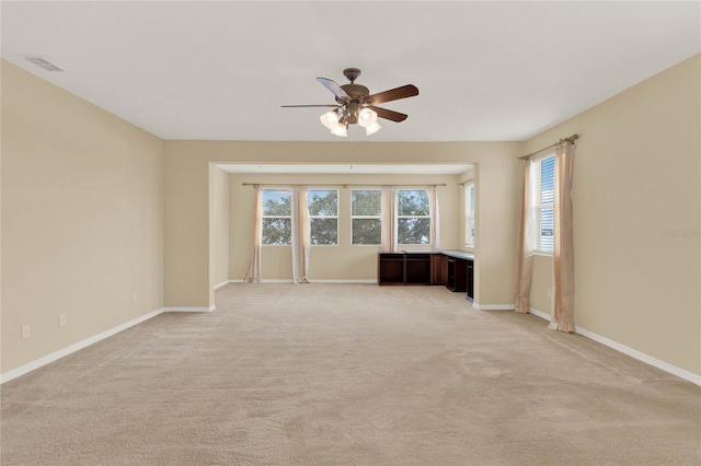 carpeted empty room featuring ceiling fan and plenty of natural light