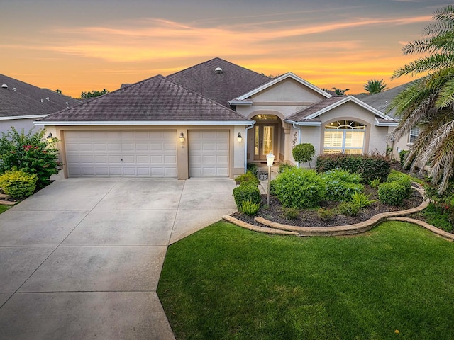 ranch-style home featuring a garage and a yard