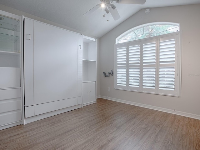 empty room with ceiling fan, lofted ceiling, and light hardwood / wood-style flooring