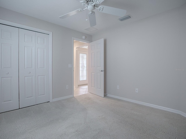 unfurnished bedroom with ceiling fan, light colored carpet, and a closet