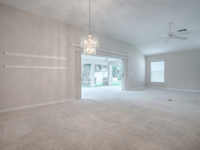 carpeted empty room featuring ceiling fan with notable chandelier and vaulted ceiling