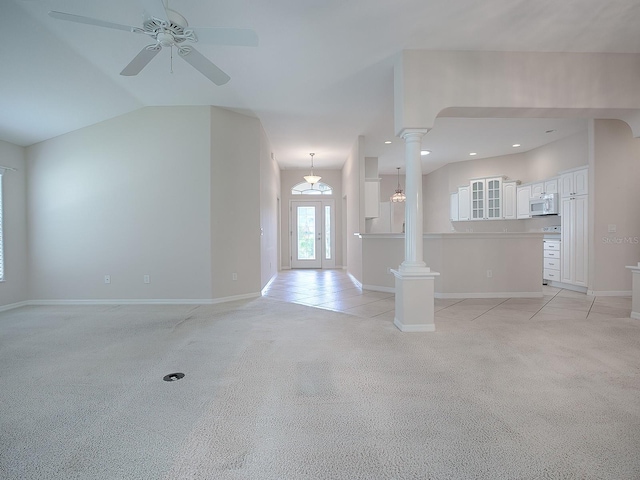 unfurnished living room featuring lofted ceiling, ornate columns, light carpet, and ceiling fan with notable chandelier