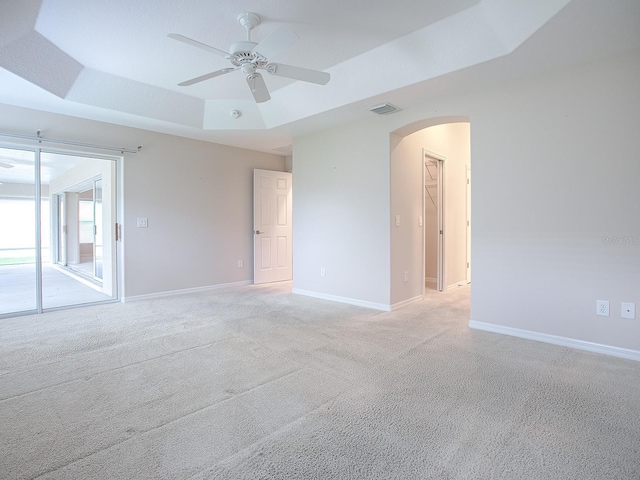 unfurnished room featuring light carpet, a raised ceiling, and ceiling fan