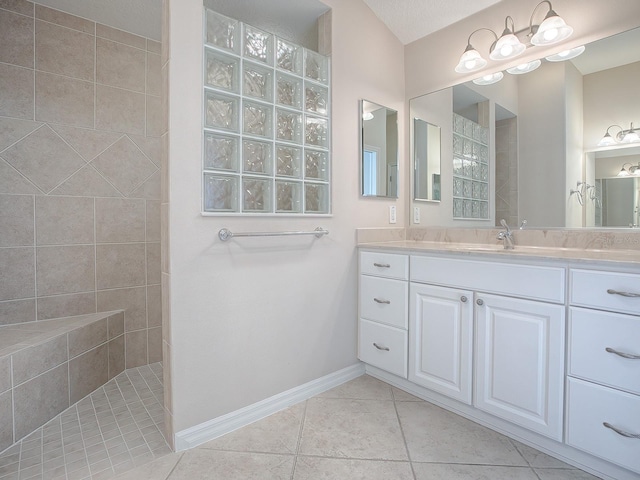 bathroom with tile patterned floors, vanity, and tiled shower