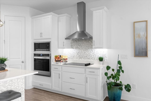 kitchen with white cabinetry, wall chimney exhaust hood, stainless steel oven, and built in microwave