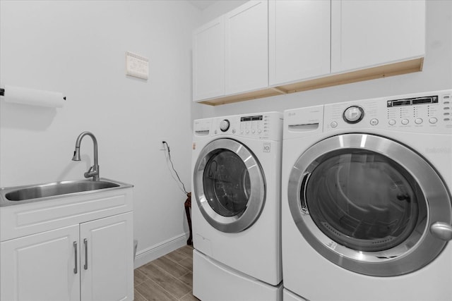 clothes washing area featuring cabinets, sink, and washing machine and clothes dryer