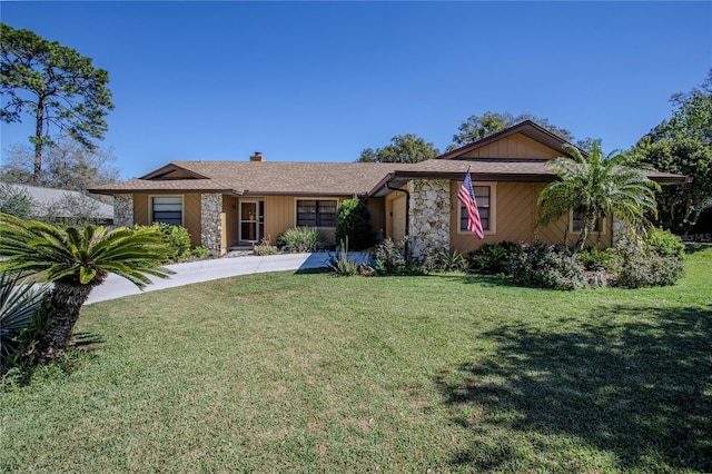 single story home featuring stone siding, a chimney, and a front yard