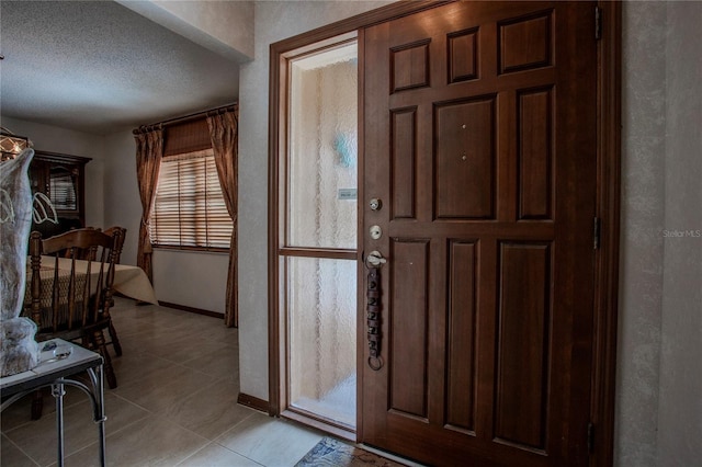 entrance foyer featuring light tile patterned floors, a textured ceiling, and baseboards