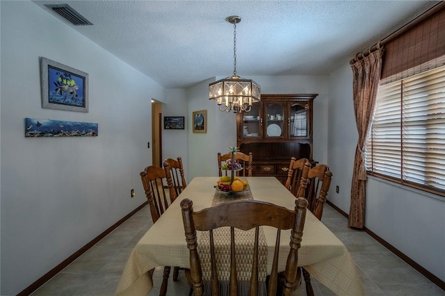 dining space featuring baseboards, visible vents, lofted ceiling, a textured ceiling, and a chandelier