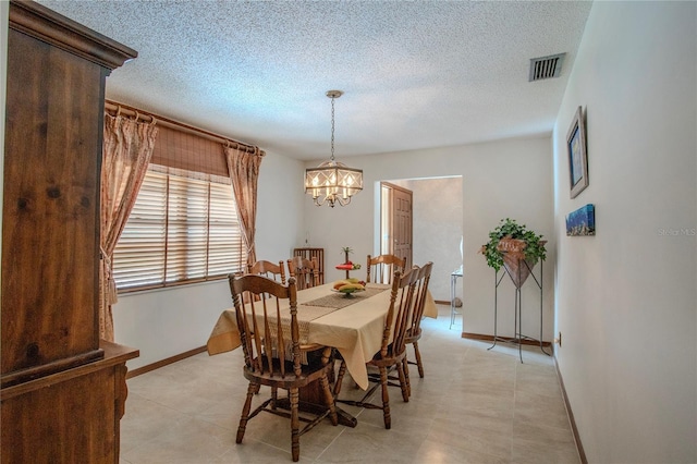 dining space with baseboards, a notable chandelier, visible vents, and a textured ceiling