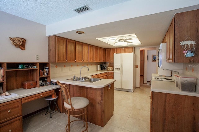 kitchen featuring white refrigerator with ice dispenser, visible vents, light countertops, a sink, and a peninsula