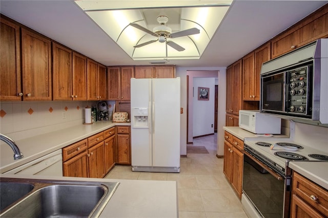 kitchen with brown cabinets, white appliances, and light countertops