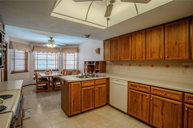 kitchen with a peninsula, white appliances, a sink, a ceiling fan, and light countertops