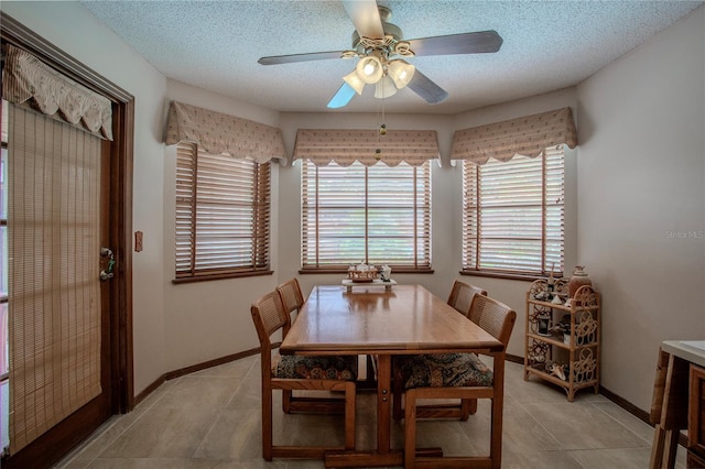 dining room with a ceiling fan, a textured ceiling, baseboards, and light tile patterned floors