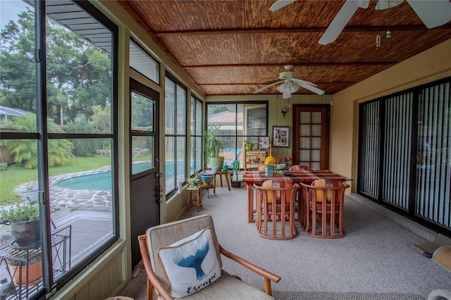 sunroom / solarium featuring beam ceiling, wood ceiling, and a ceiling fan