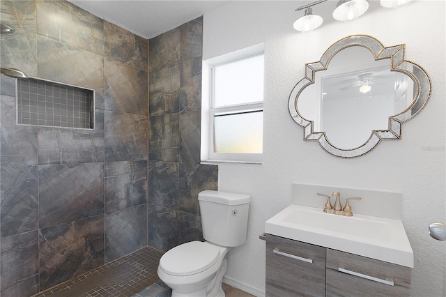 bathroom featuring toilet, vanity, and a tile shower