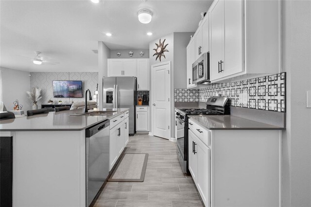 kitchen with decorative backsplash, stainless steel appliances, sink, white cabinets, and light hardwood / wood-style floors