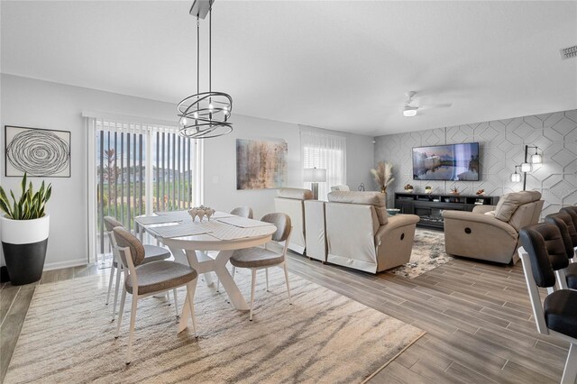 dining space with ceiling fan with notable chandelier and light hardwood / wood-style flooring